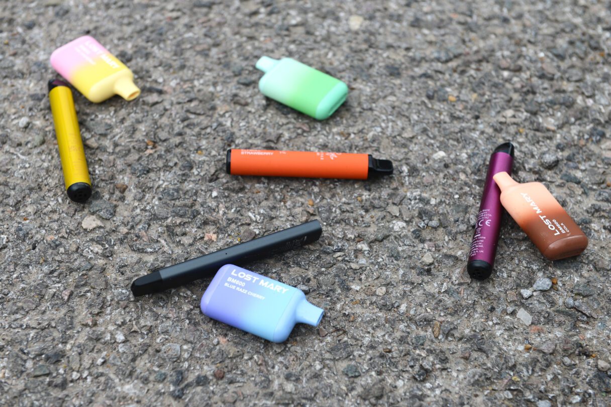 Various disposable vapes lie discarded on the street.