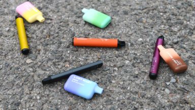Various disposable vapes lie discarded on the street.