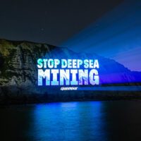 Stop deep sea mining projection on sea cliffs at night