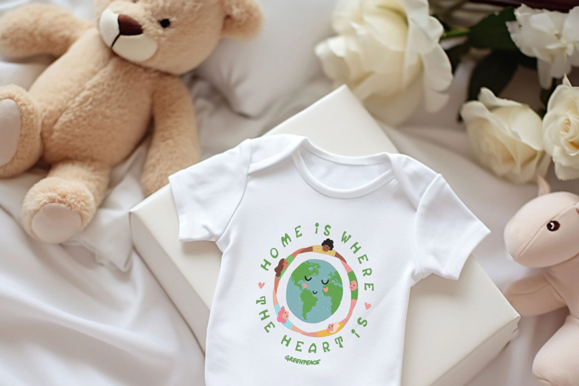 Product show of a baby grow with design saying home is where the heart is and a picture of people holding hands around the world