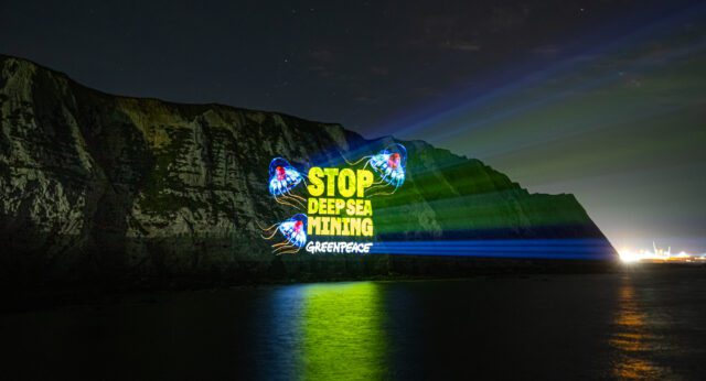 'Stop Deep Sea Mining' is projected on the White Cliffs of Dover at night, with creatures from the deep sea displayed around the words.