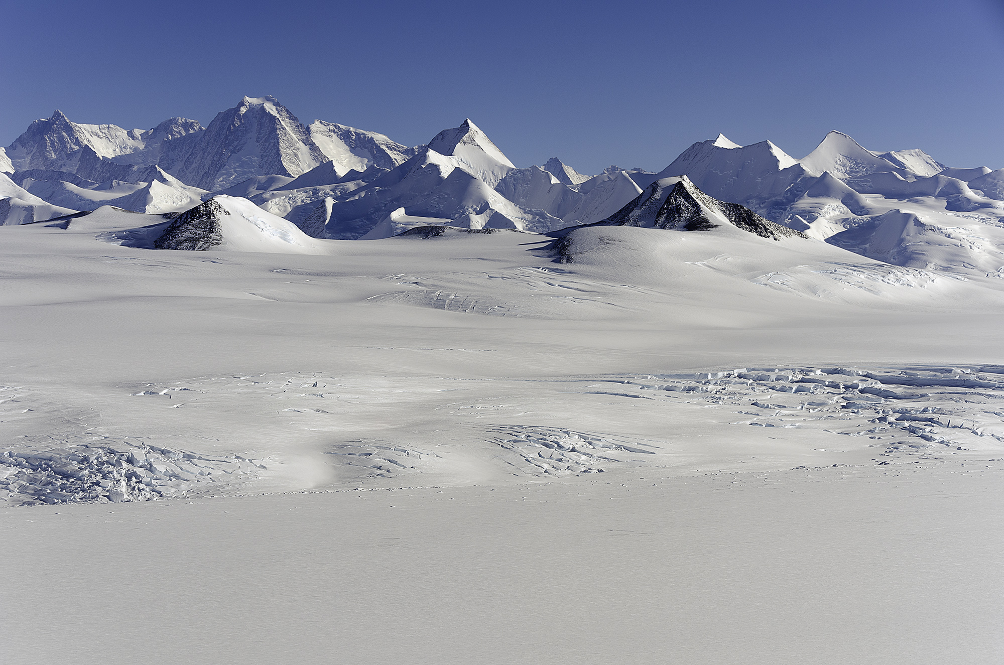 Snow-covered polar landscape with a jagged mountain range on the horizon,