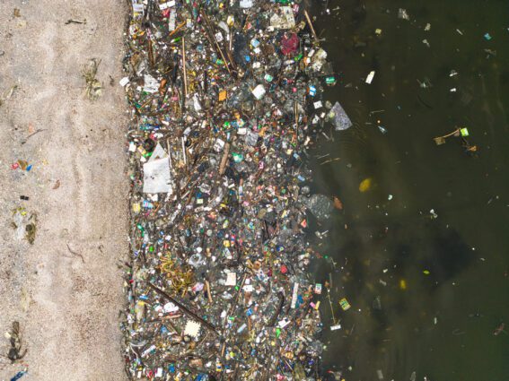 Aerial view of a thick soup of plastic waste clustered along the waterline of a beach.