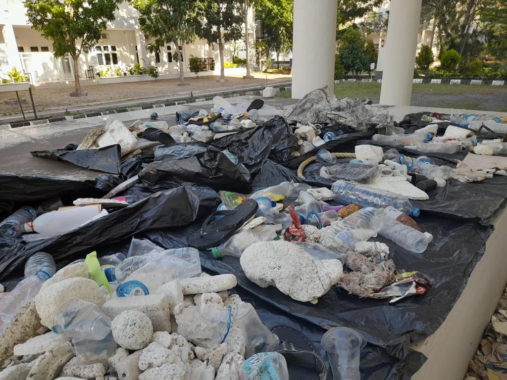 Plasic bottles and other waste laid out on black plastic sheeting