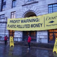 Activists outside the grand entrance to Unilever's London office display a banner that says 'profit warning: plastic polluted money'.