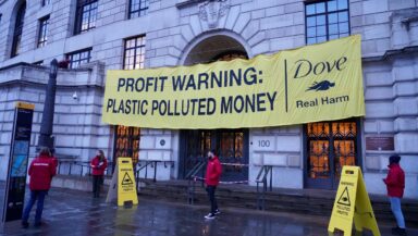 Activists outside the grand entrance to Unilever's London office display a banner that says 'profit warning: plastic polluted money'.