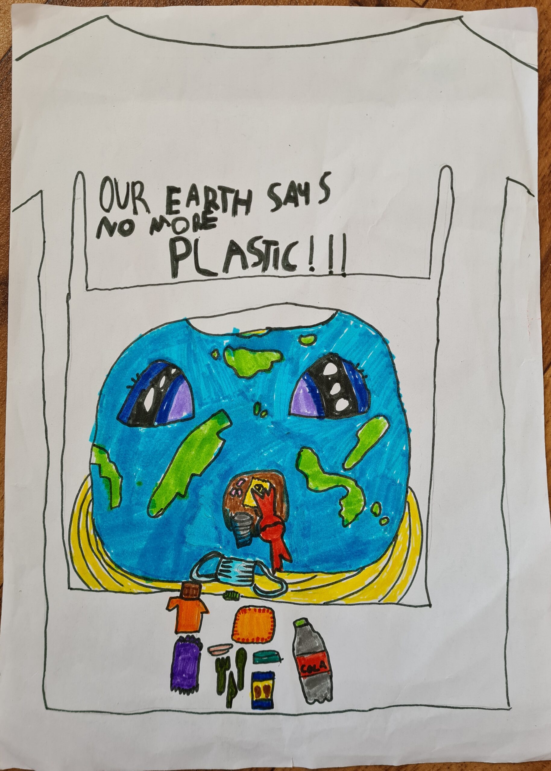 Child’s drawing showcasing the outline of a plastic bag with a drawing of the Earth inside and plastic pollution items such as a face mask, plastic bottle and cutlery. As well as a slogan reading ‘Our earth says no more plastic!!!’