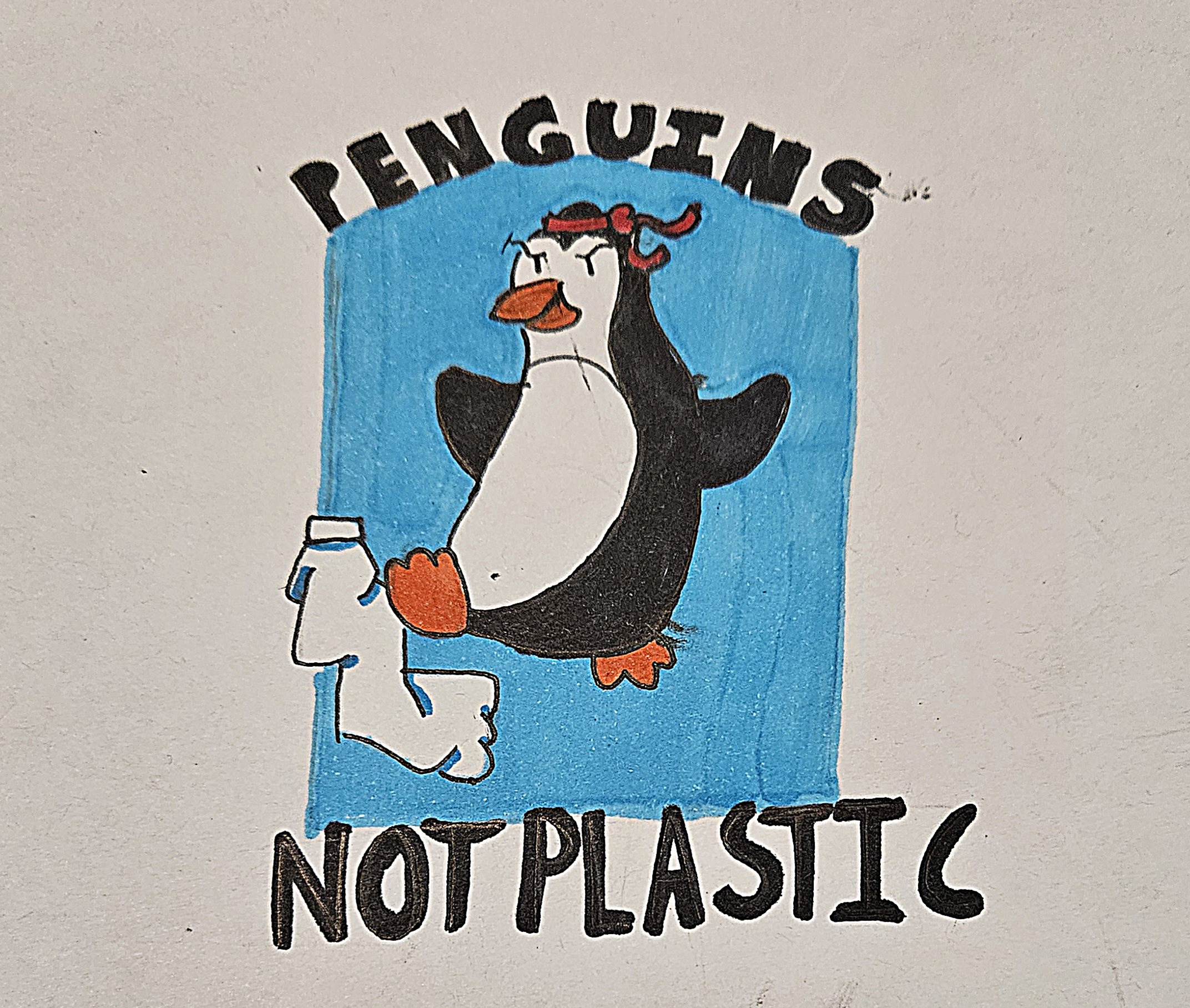 Child’s drawing featuring the slogan ‘Penguins not plastic’ illustrating a penguin with a red karate headband kicking a plastic water bottle