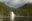 A waterfall runs out from a densely-forested hillside and into a calm lake in the Great Bear Rainforest