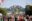 Crowds at a festival walk under a colourful wooden archway bearing the slogan 'be wild'.
