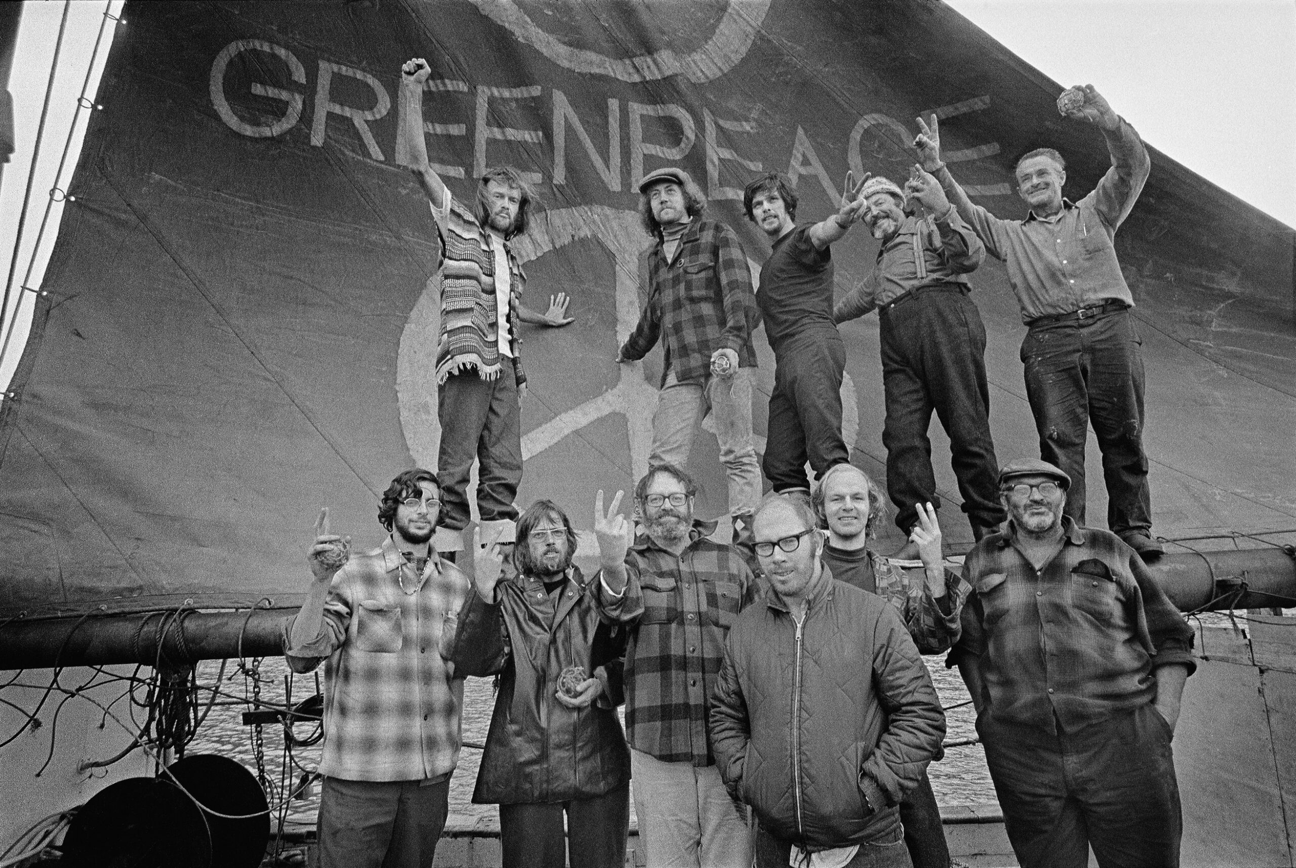 group of people stand in front of original greenpeace logo