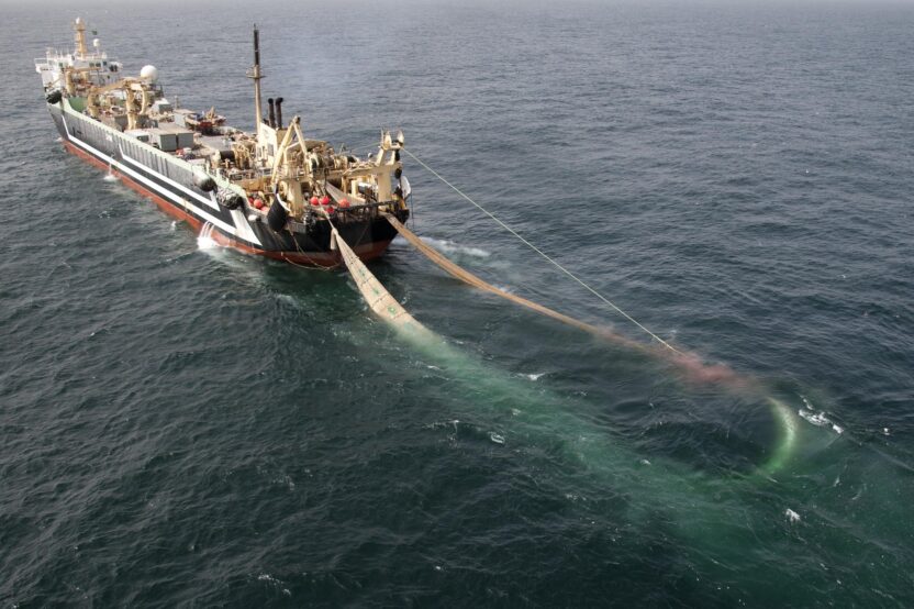 Aerial view of a giant fishing ship with a net trailing behind it