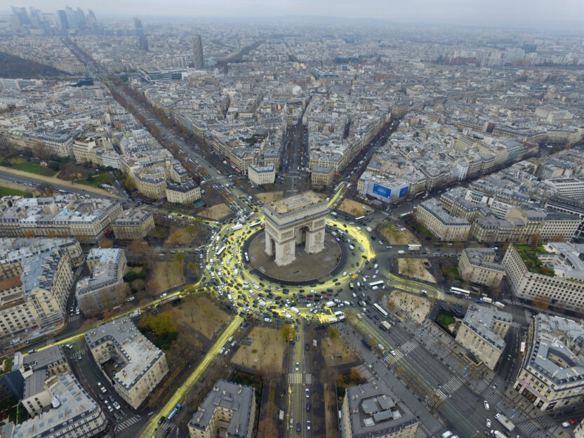 Traffic spreading bright yellow paint from the Arc de Triomphe onto surrounding roads, creating the shape of a sun when seen from above.