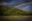 Rainbow over a river. Trees gently slope up from the river bank.