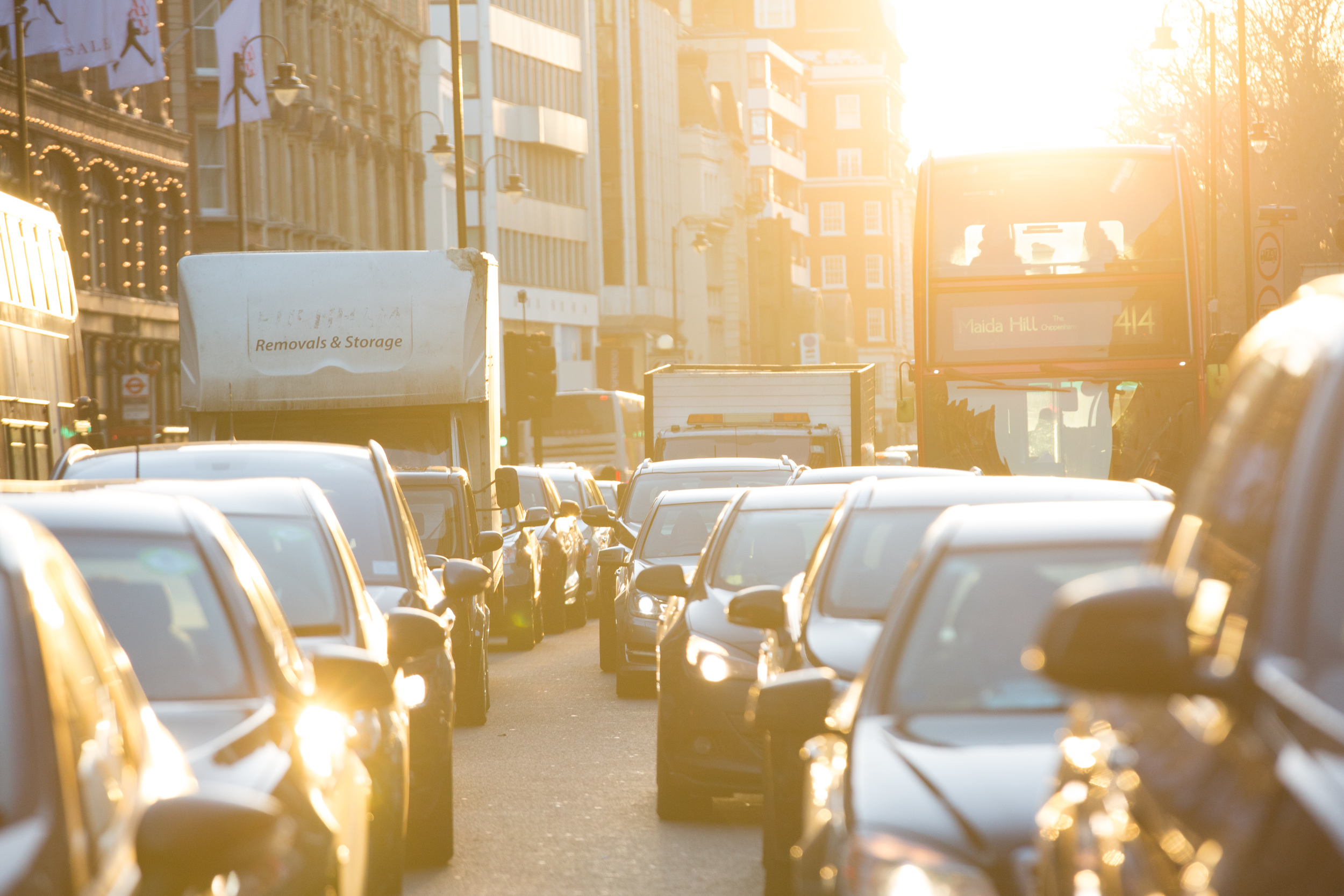 Cars, vans and a bus in standstill traffic with low sun in the background