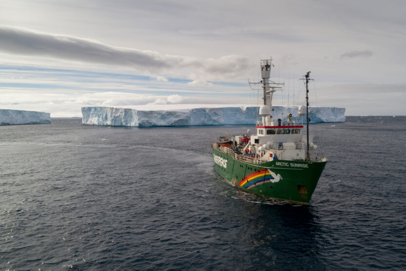 Greenpeace ship sailing through large icebergs