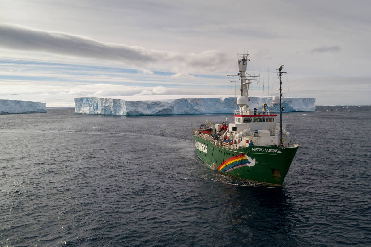 Greenpeace ship sailing through large icebergs
