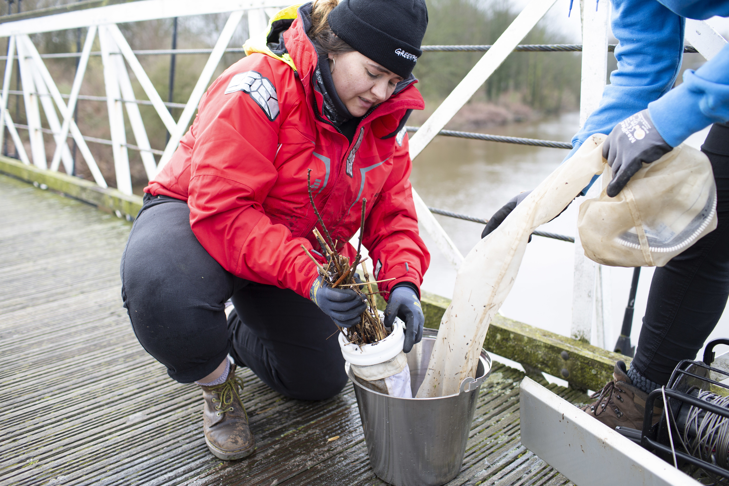 A woman removes river debris from a sampling instrument.