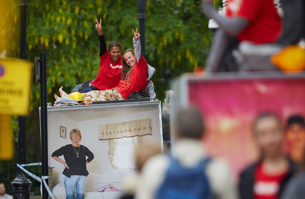 Two activists in matching red t-shirts smile and hold up peace signs