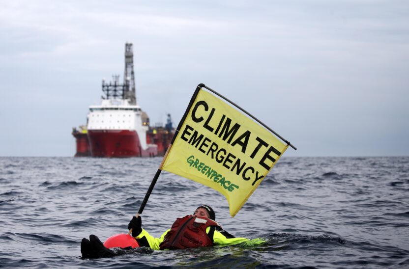 Swimmer in front of an oil rig with a banner that says 