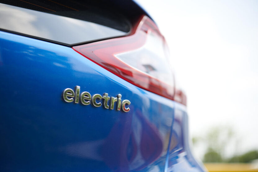 Closeup of the back of a modern car with the word 'electric' embossed on the paintwork.