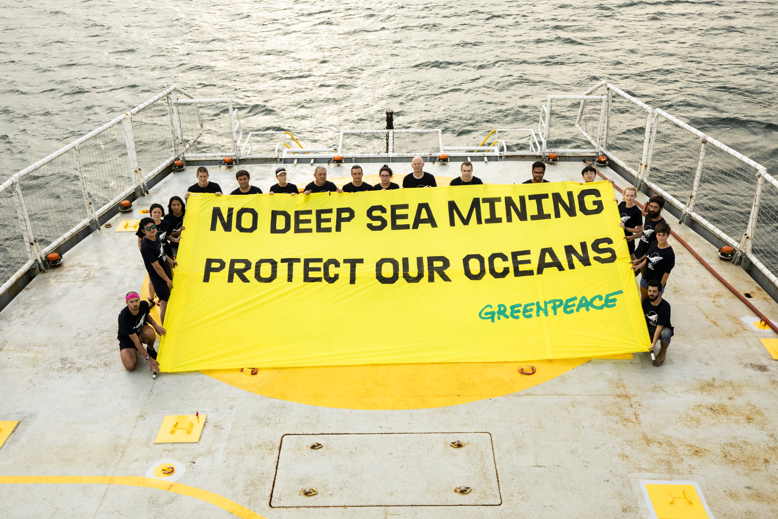 ship crew hold a banner on deck