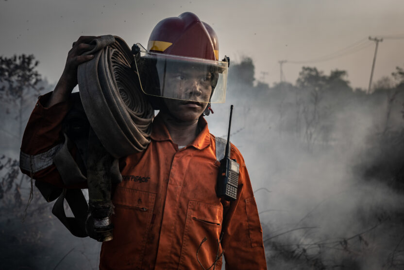 Person in a safety hat carrying a rolled up water pipe