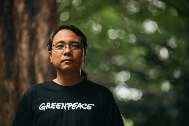 Yeb Saño stands in a forest, looking past the camera pensively.