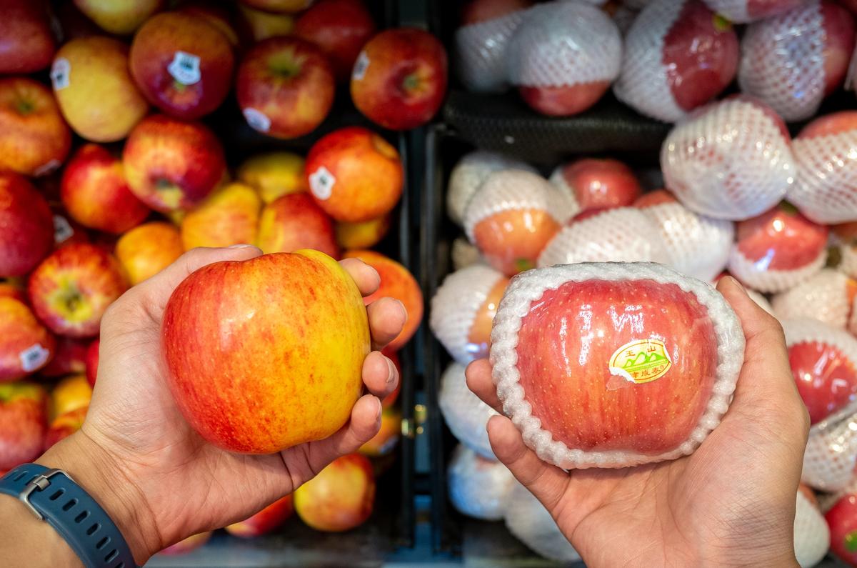 Two apples, one wrapped in plastic and polystyrene, and one loose.