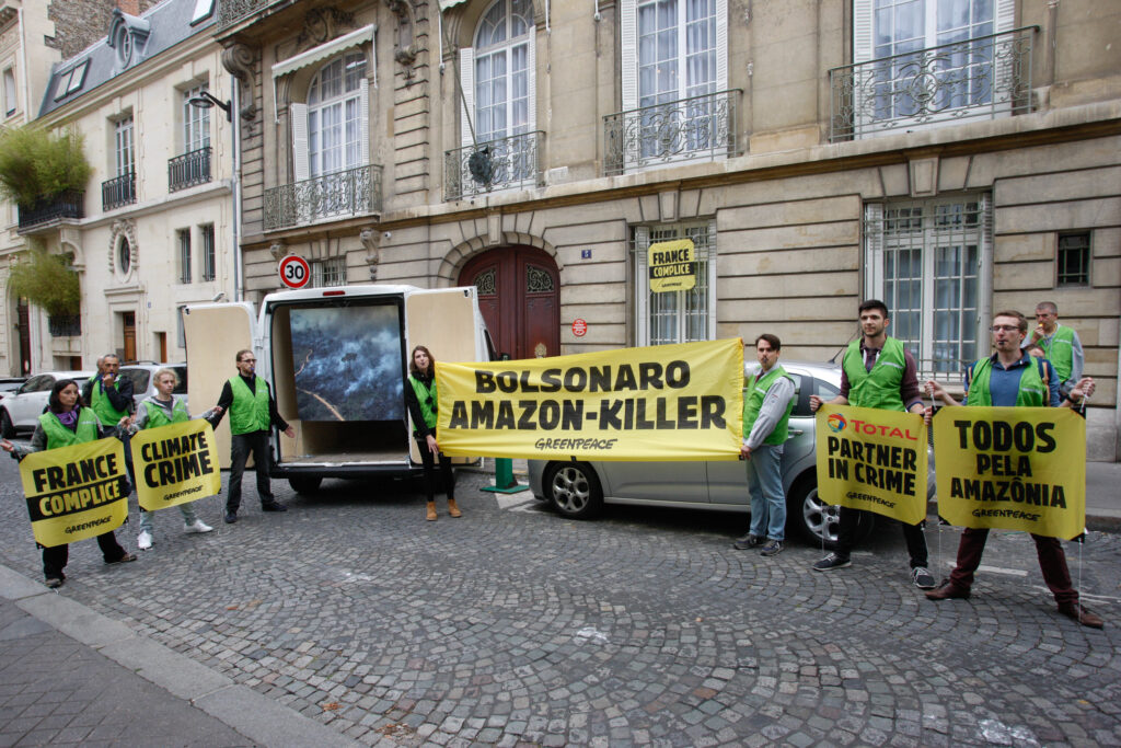 Protesters outside the Brazilian ambassador's residence in Paris with large yellow banners banners reading "Bolsonaro Amazon Killer"