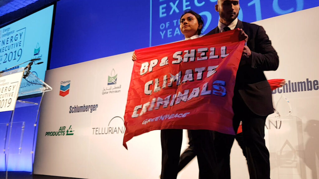 An activist holds up a banner saying 'BP and Shell climate criminals'