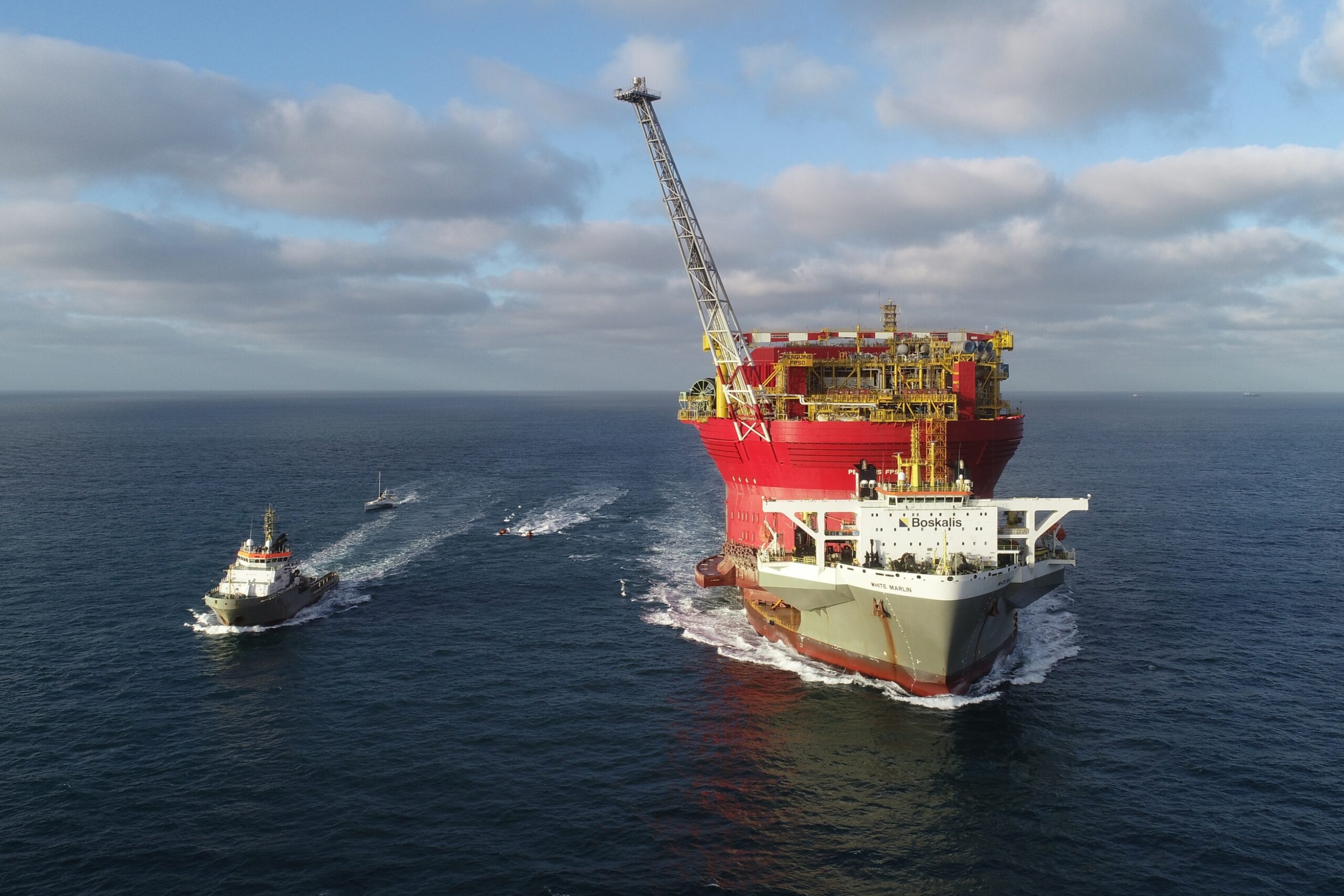 Aerial shot of Shell's ship with the giant oil platform on the deck, accompanied by a smaller escort ship.