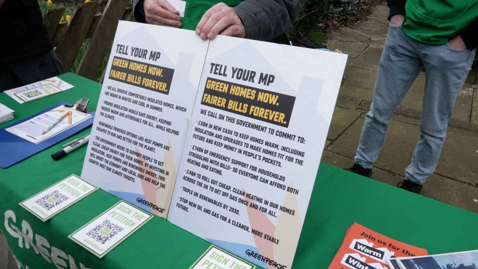 Information board on a campaign stall that says tell your mp green homes now fairer bills forever, with further information written below