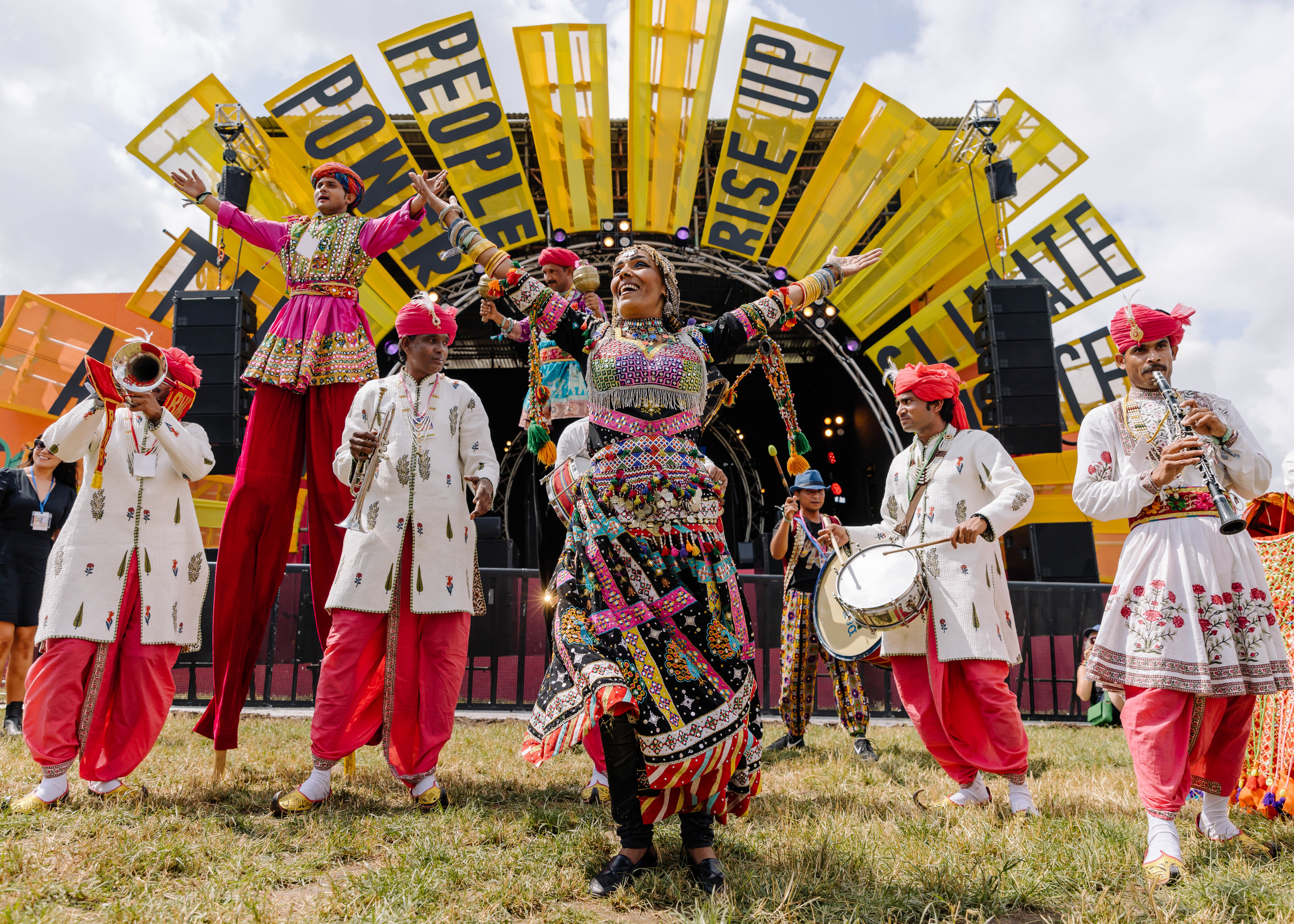 Performers dressed in bright costumes in the Greenpeace field at Glastonbury.