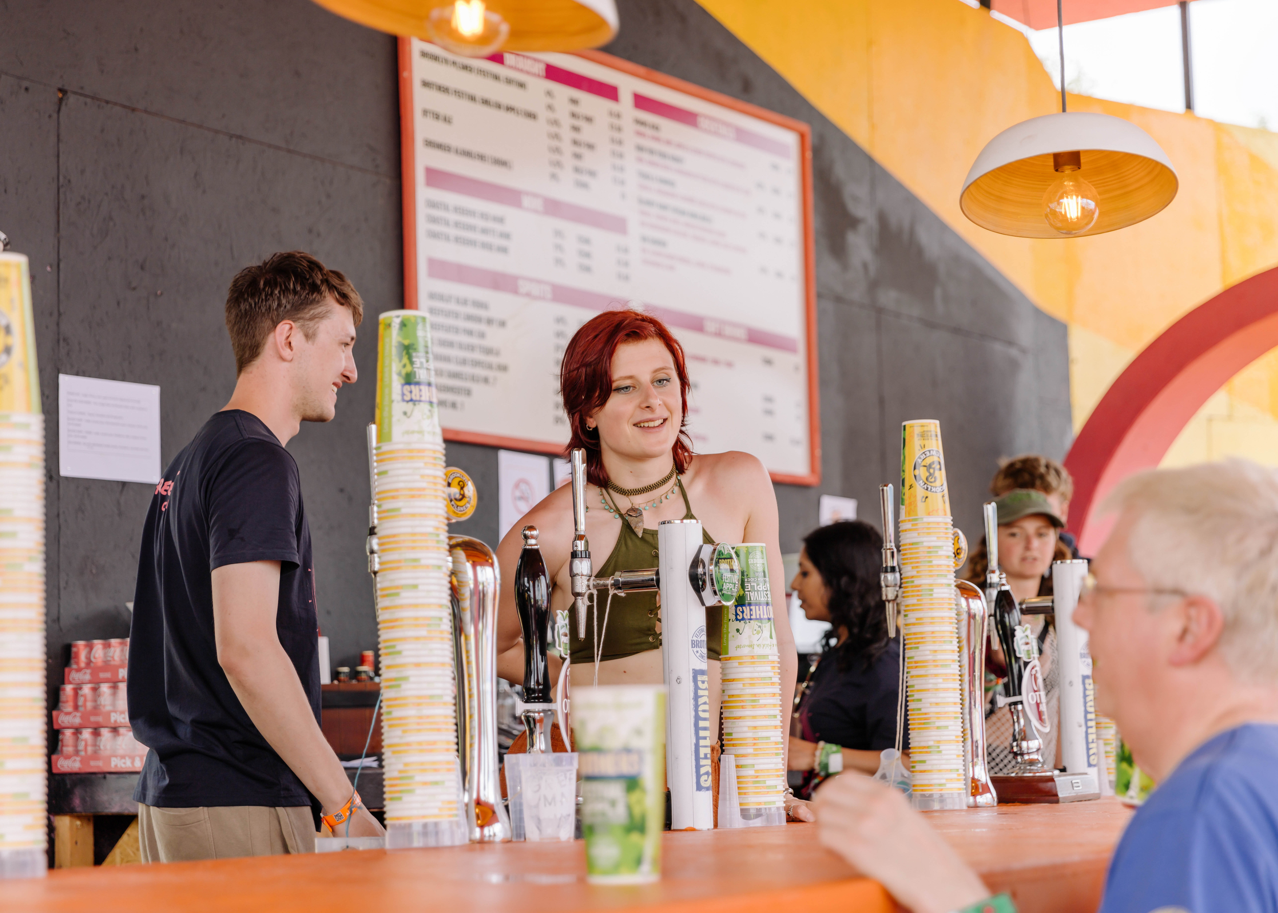 Smiling bar staff with reusable cups at the Greenpeace field in Glastonbury