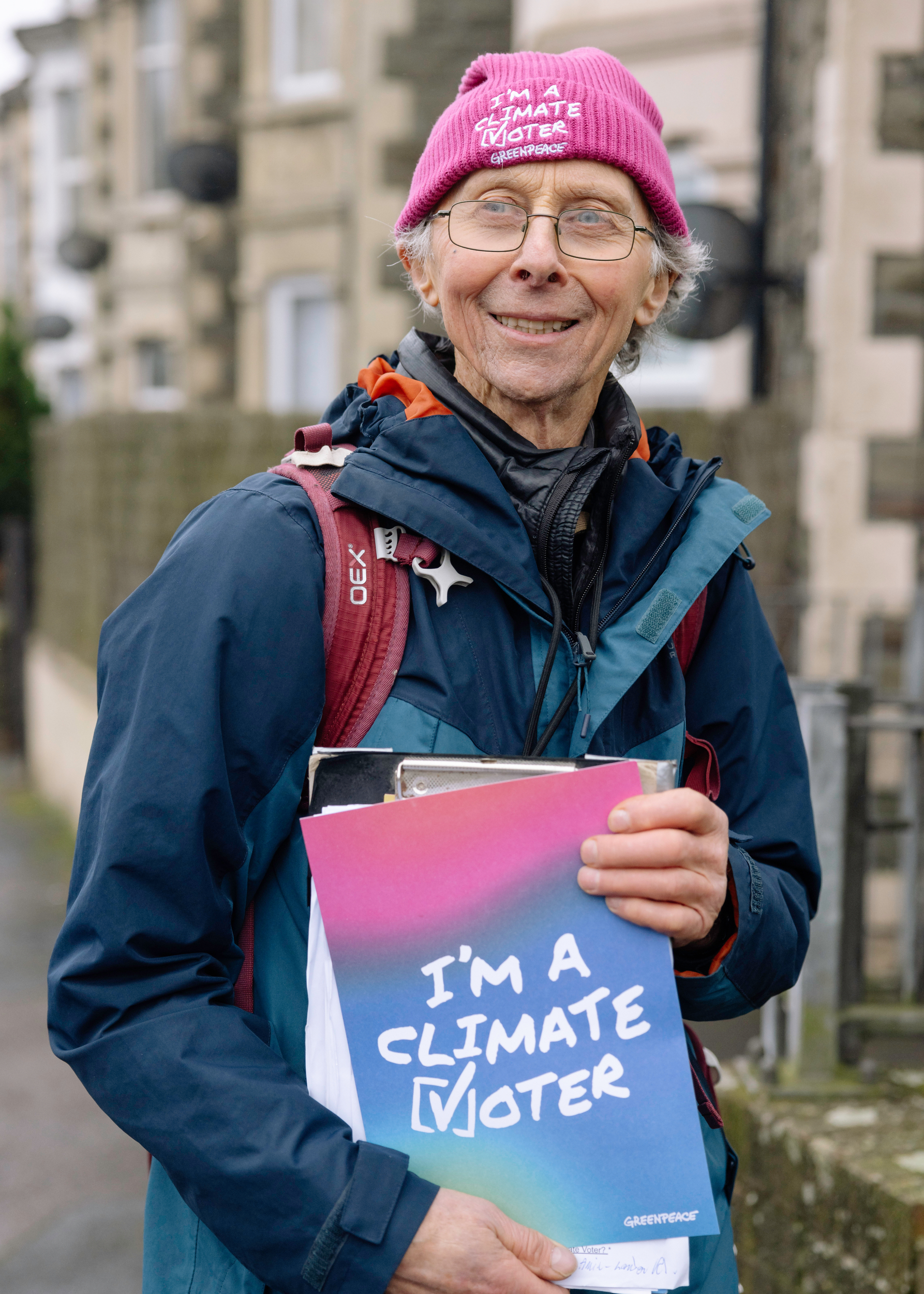 An older man holds a colourful "I'm a climate voter" poster