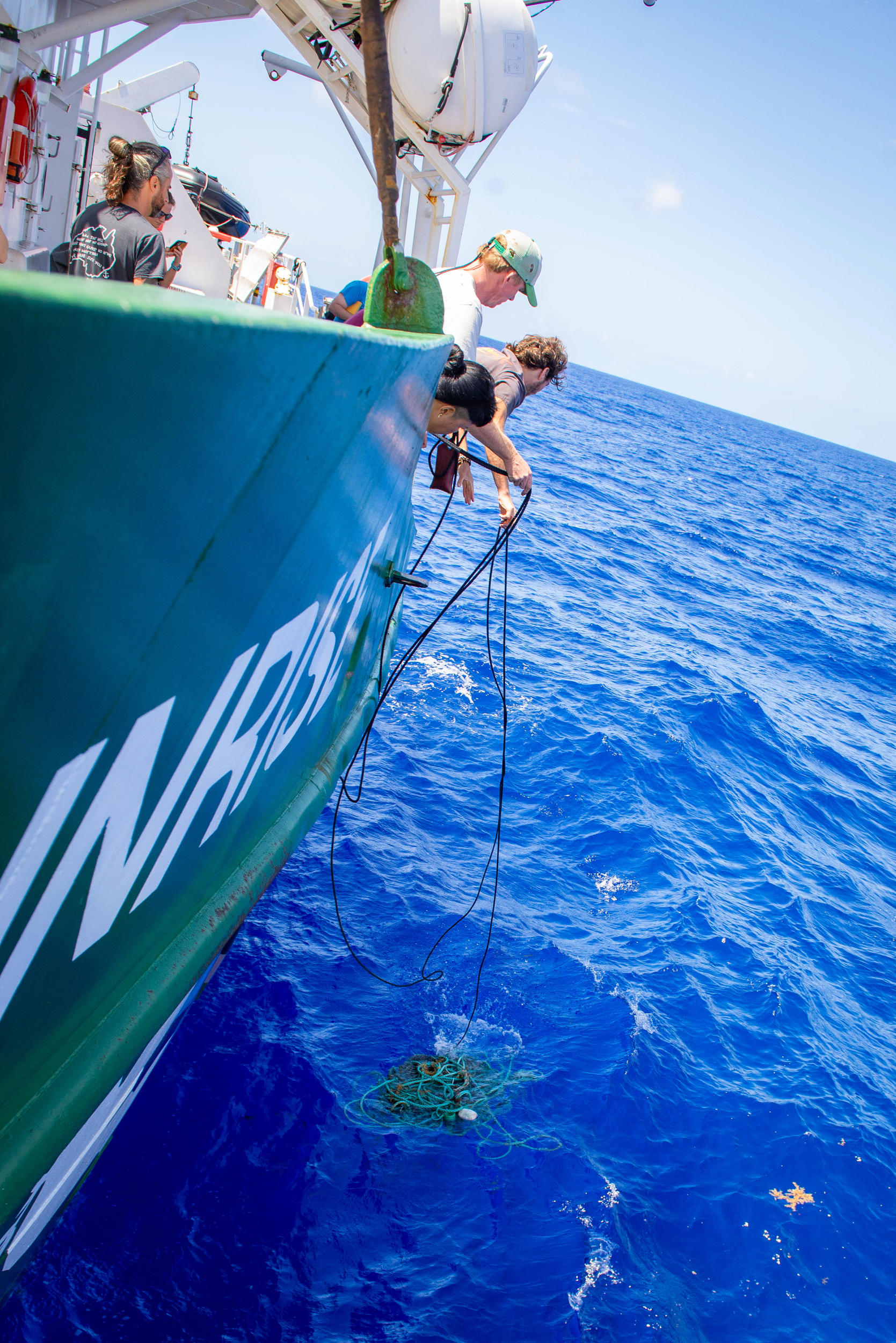 Side of the Greenpeace ship with someone leaning over with ropes