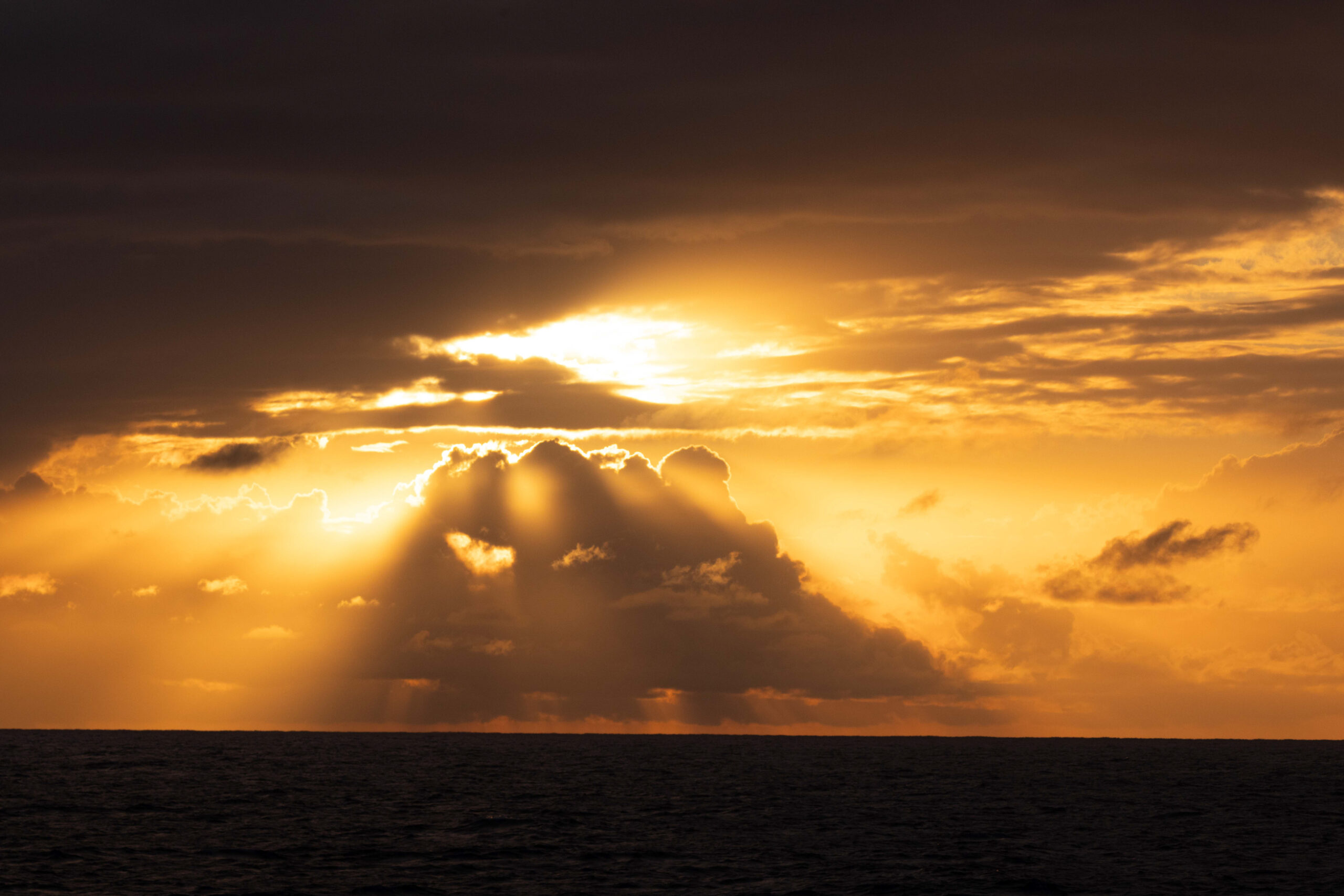 A beautiful yellow sunset framed by black sea and dark clouds