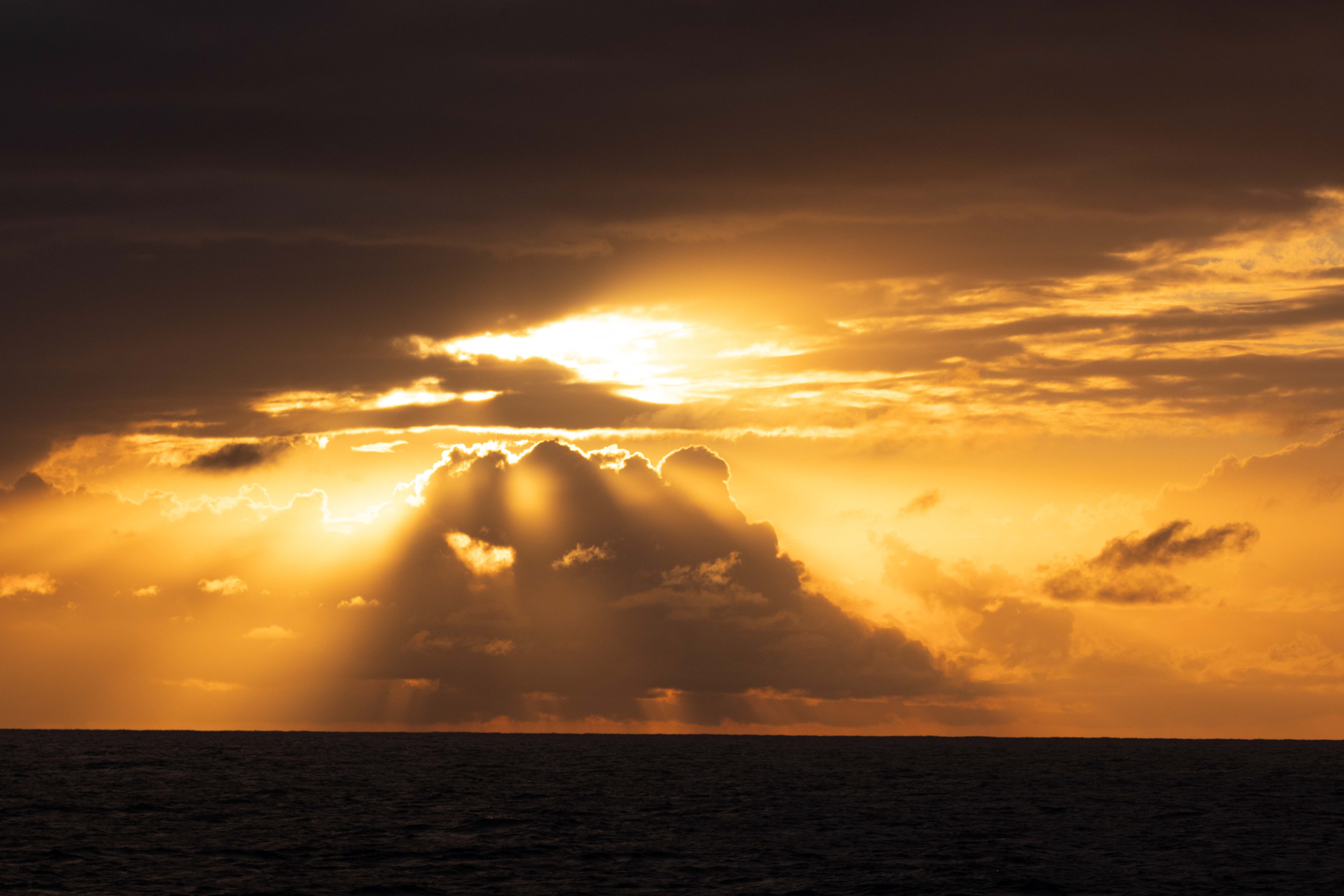 A beautiful yellow sunset framed by black sea and dark clouds