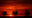Three connected gas platforms (they look like oil rigs) against a deep red sunset.
