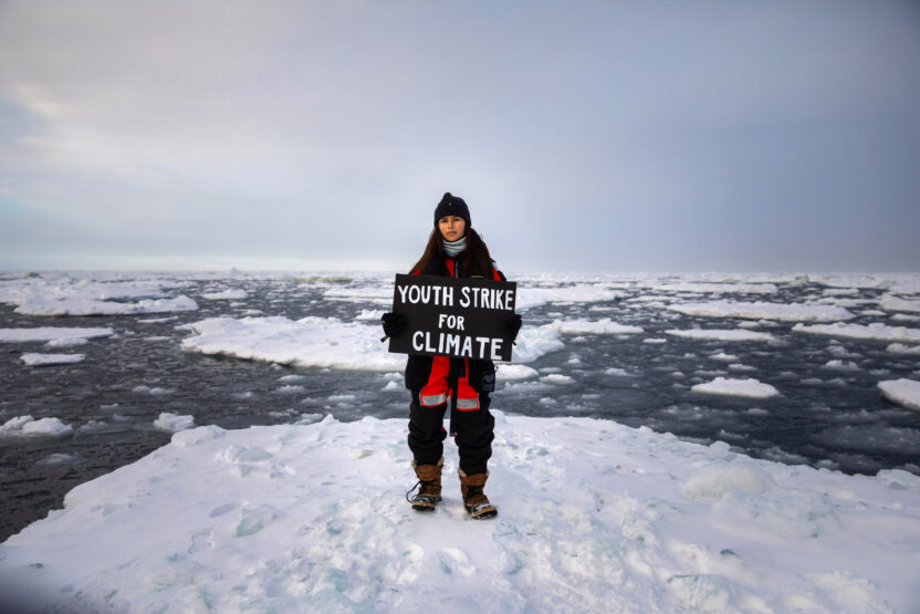 Mya-Rose Craig standing on an ice floe holding a sign reading 'Youth strike for climate'