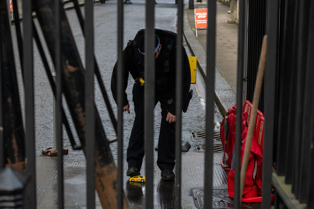 A police officer traps one of the remote controlled cars with his foot.
