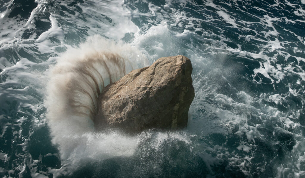 A boulder splashes into the water