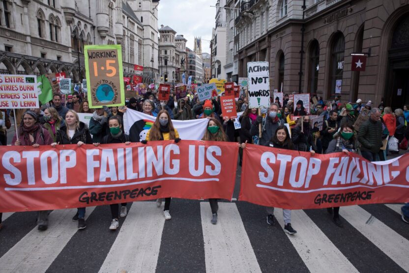 A large group of climate marchers hold up an array of colourful homemade signs.
