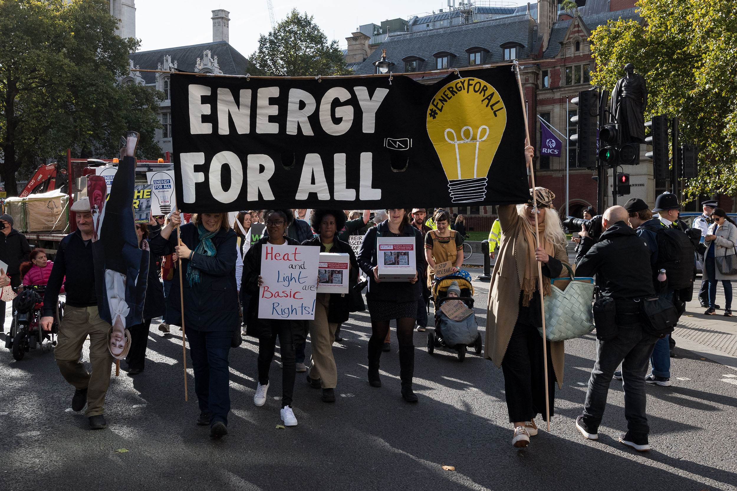 Fuel poverty protesters walk along a street with banners reading 