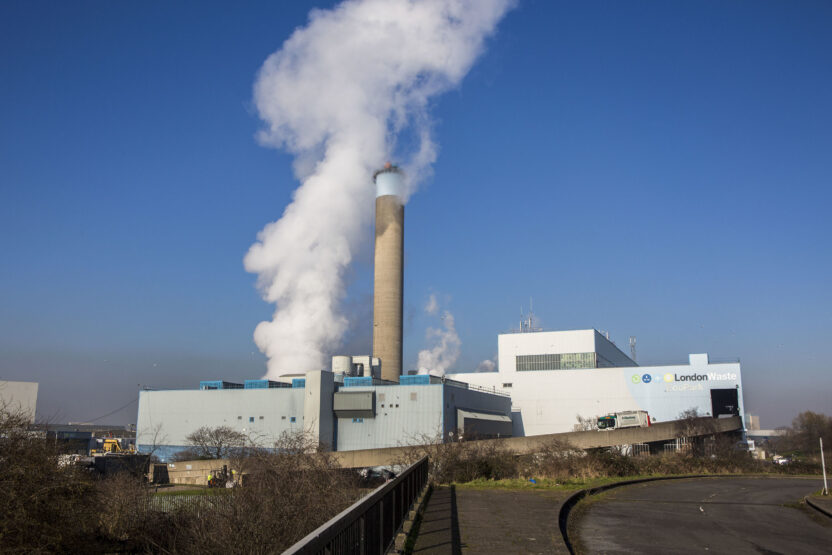 Steam bellows from a large chimney in an industrial waste site