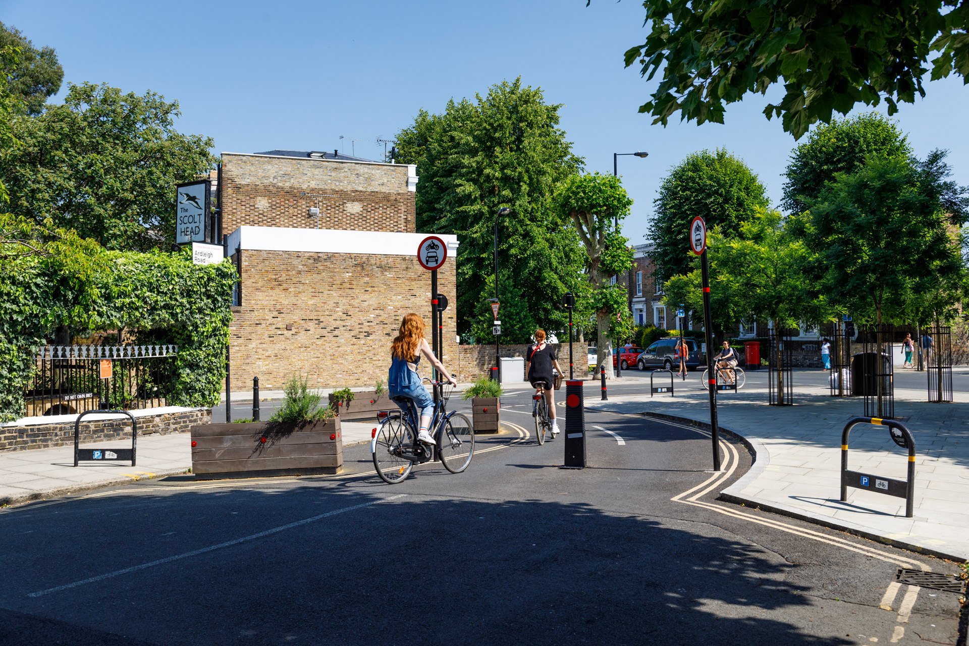 Two women riding through a traffic filter on a residential street