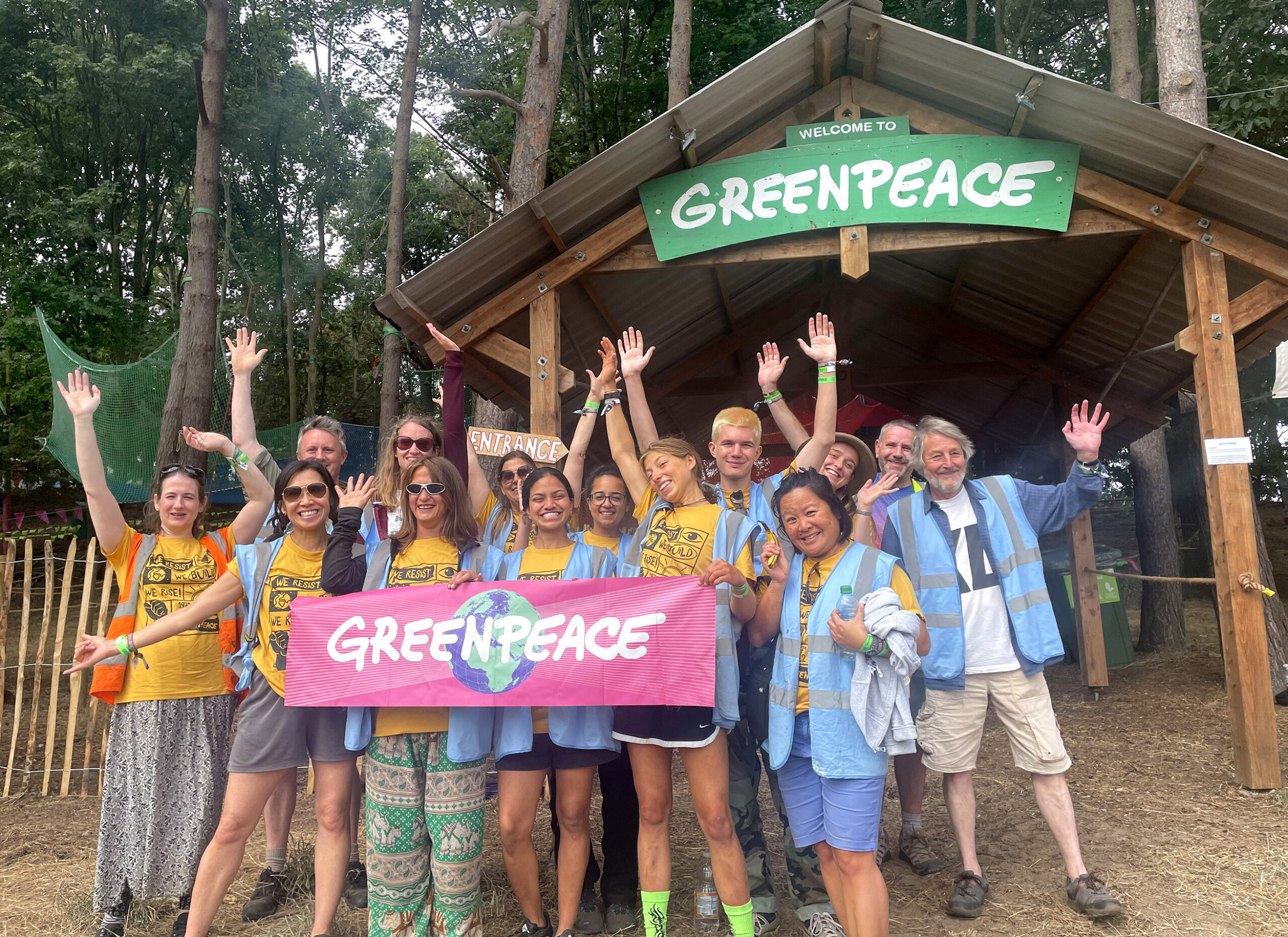 Greenpeace volunteers pose for a group photo in front of a beautiful forest.