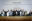 World leaders standing in a line and cheering in front of a United Nations conference backdrop during negotiations for the Paris Climate Agreement
