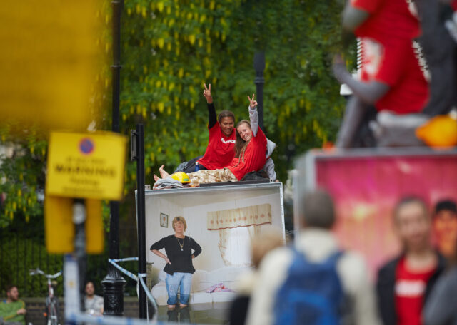 Two activists on top of a shipping container smile and hold up peace gestures to the camera